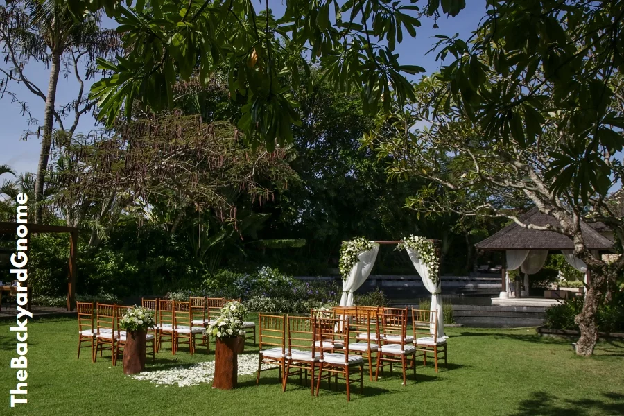 Beautiful romantic outdoor wedding setup in tropical garden, wooden chairs and simple gazebo decorated with white flowers - Part 1
